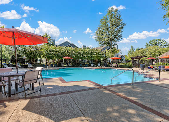 a swimming pool with tables and umbrellas next to it