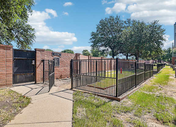 a fenced in area with a fence and a brick building