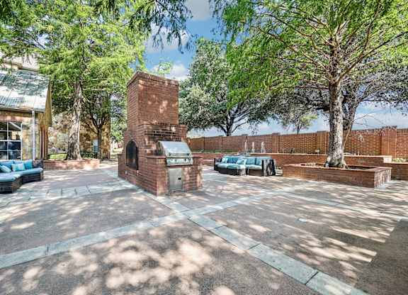 a courtyard with trees and a brick building with a grill