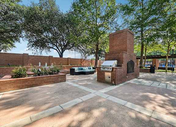a brick fireplace in the middle of a courtyard with trees