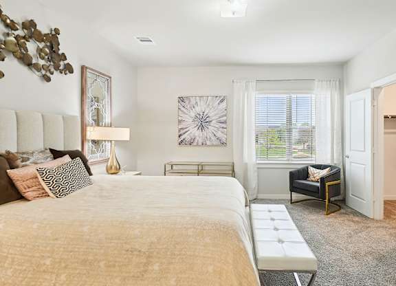 A bedroom with a large bed and a chair by the window.