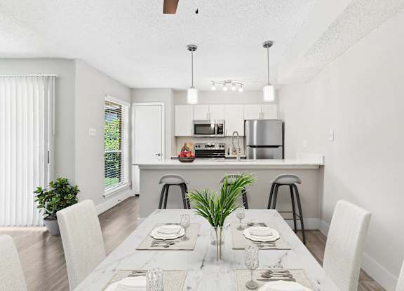 a dining area with a table and chairs and a kitchen in the background