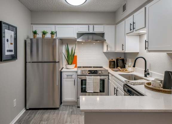 Bright kitchen with white shaker cabinets, stainless appliances, and quartz peninsula seating.