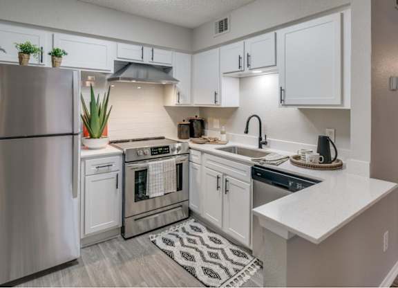 Modern L-shaped kitchen featuring breakfast bar, stainless dishwasher, and matte-black faucet.