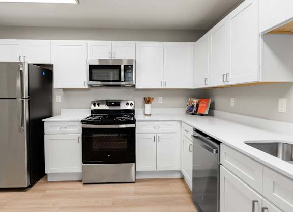 Modern kitchen featuring white shaker cabinets, stainless steel appliances, and expansive countertop workspace.
