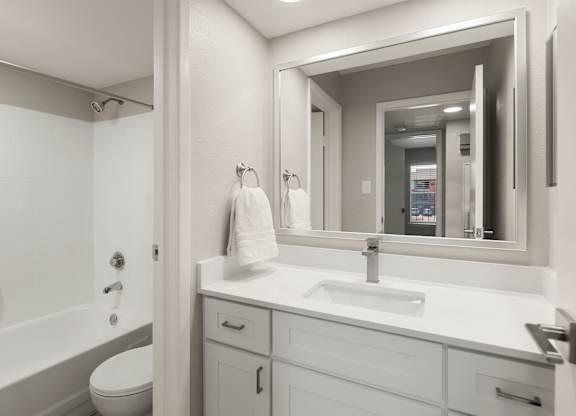 Contemporary bathroom with white vanity, framed mirror, and tub-shower combination at Heritage at Valley Ranch.
