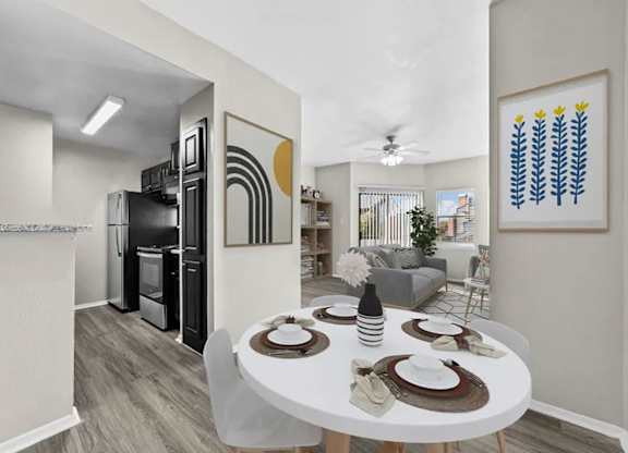 Open dining and living area with adjacent kitchen, large window, and wood-style flooring.