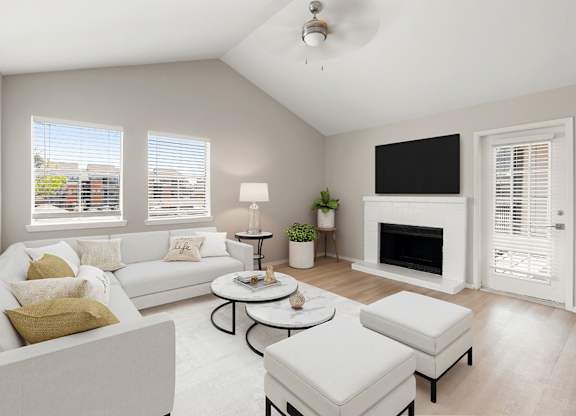 Bright living room with vaulted ceiling, fireplace, large windows, and soft neutral finishes.