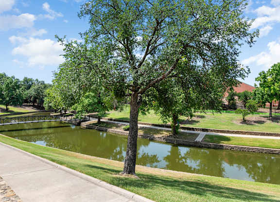 Tree-lined pond and walking trail with peaceful water views and landscaped grounds.