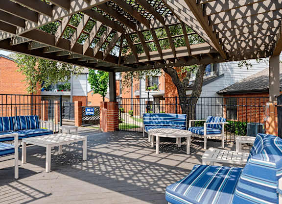 Pergola-covered outdoor lounge with cushioned seating beside the pool deck.