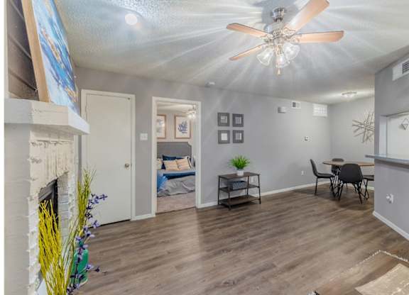 A room with a fireplace, a ceiling fan, and a dining table with chairs.