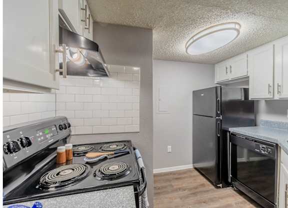 A kitchen with a black stove top oven and a black refrigerator.