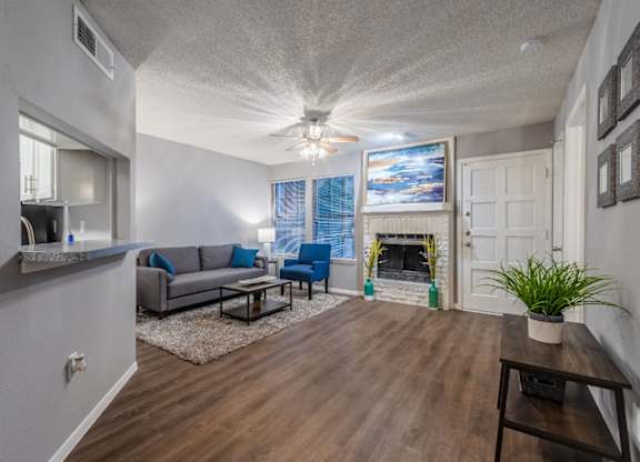 A living room with a grey couch and a wooden floor.