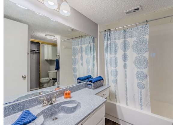 A bathroom with a shower curtain and a sink.