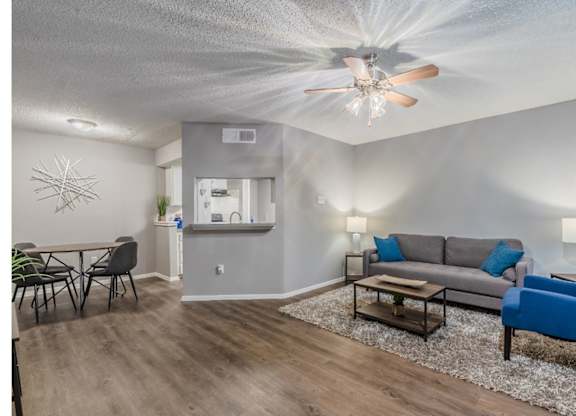 A living room with a grey couch, a blue chair, and a wooden floor.
