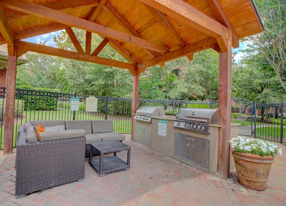 an outdoor kitchen with a grill and a seating area under a wooden awning