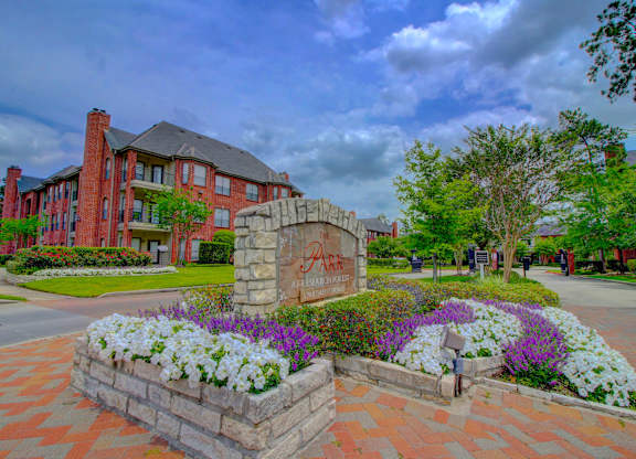 a large stone monument with flowers in front of it and a brick building in the background