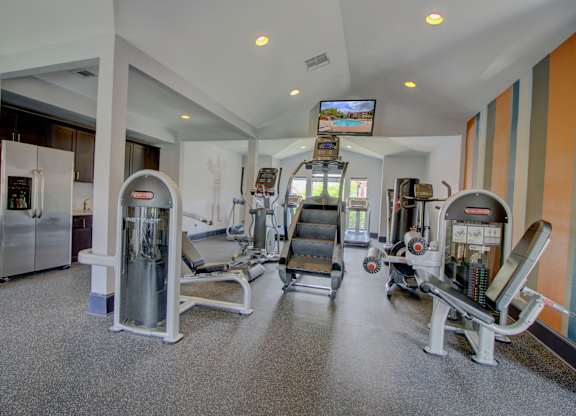 a spacious fitness room with cardio equipment and a flat screen tv