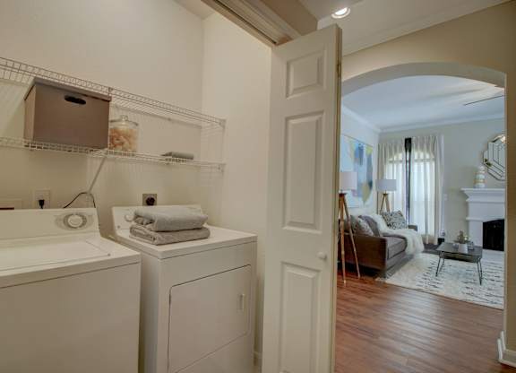 a laundry room with a washer and dryer and a living room in the background