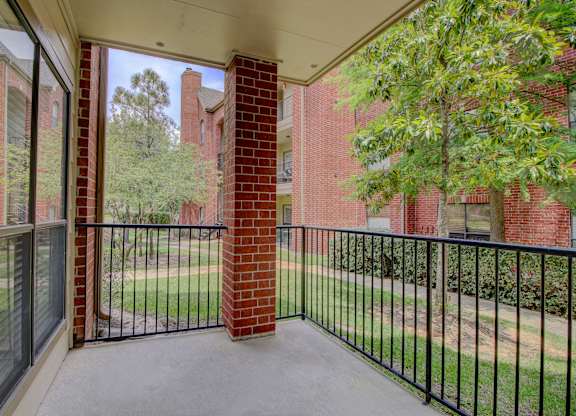a balcony with a black railing and a brick building in the background
