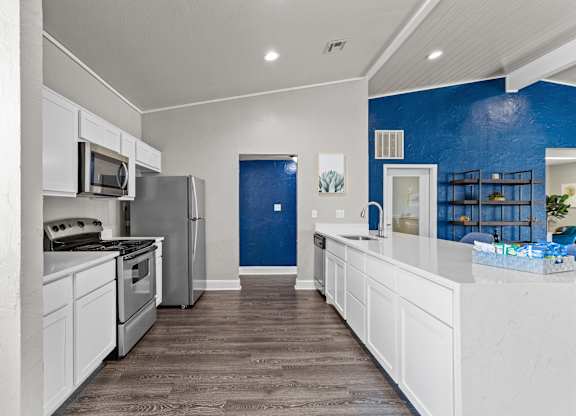 a kitchen with white cabinets and a blue wall
