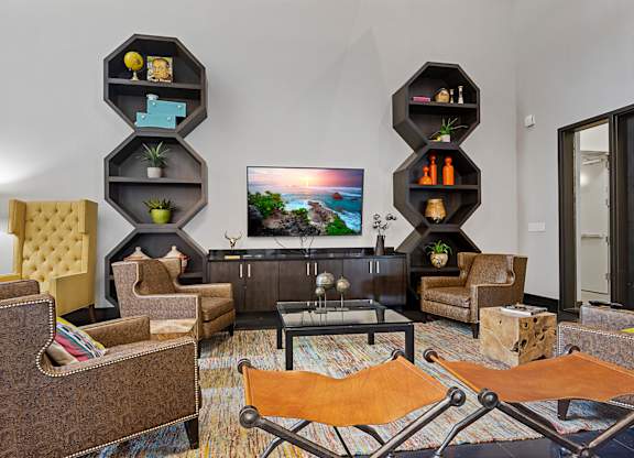 A living room with a brown sofa, a yellow chair, and a television on a black stand.