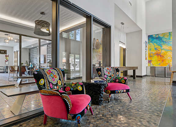 A room with a glass wall and a chair with a pink seat and black and yellow pillow.