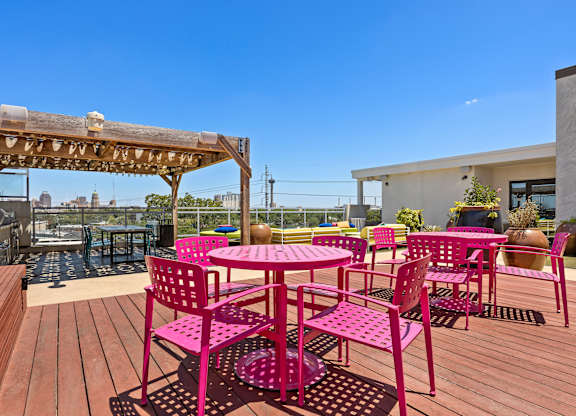 A wooden deck with pink chairs and tables.