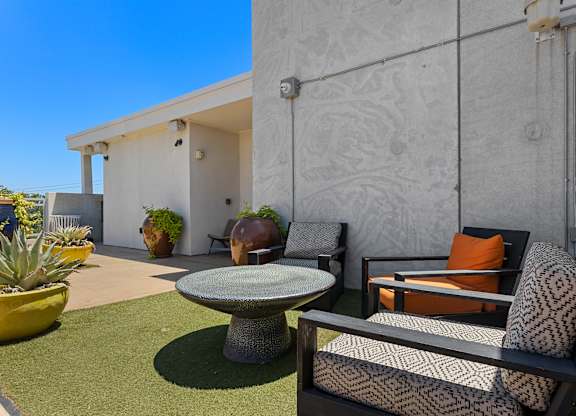A patio with a table, chairs and plants.