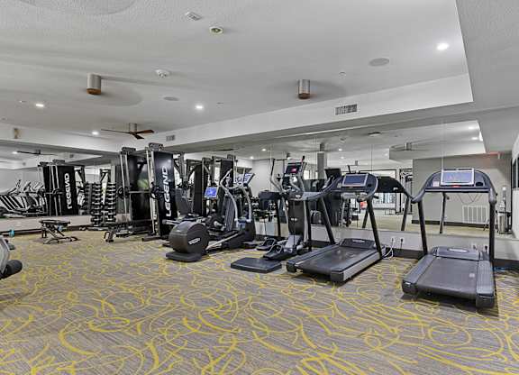 A gym with treadmills, elliptical machines, and other exercise equipment.