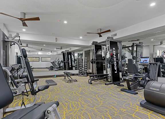 A gym with a variety of equipment including treadmills, weights, and exercise machines.