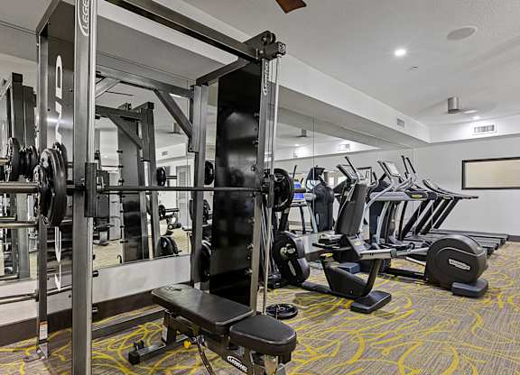 A gym with a variety of equipment including weights and cardio machines.