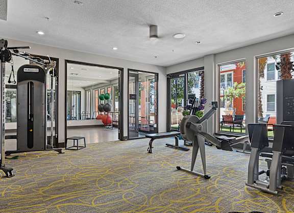 A gym with a variety of equipment including treadmills, weights, and exercise machines.