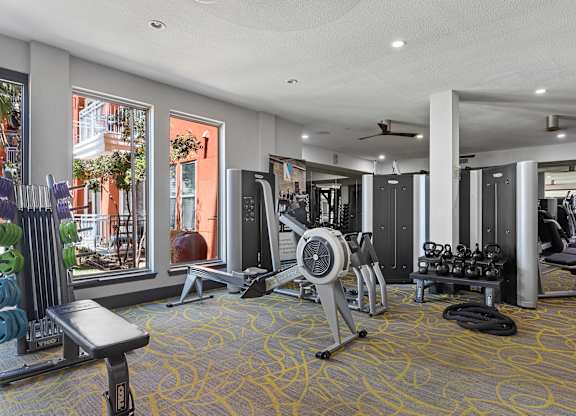 A gym with a variety of equipment including a treadmill, weights, and a bench.