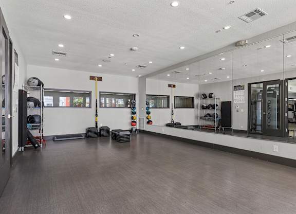 A gym with a mirrored wall and a variety of equipment.