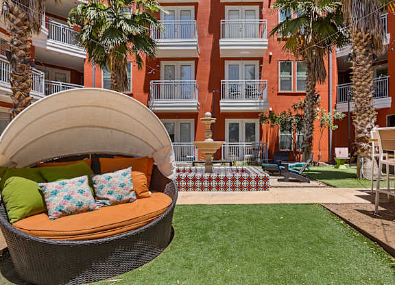 A patio with a couch and a table with a red and white checkered tablecloth.