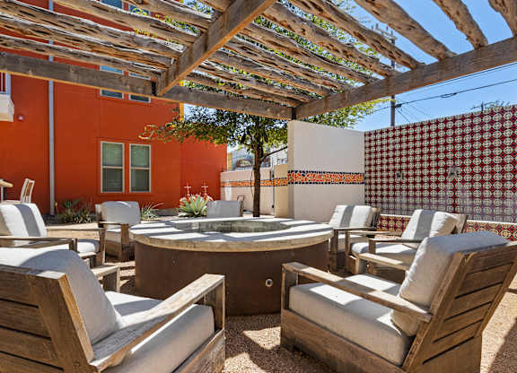 A patio with a table and chairs under a wooden pergola.