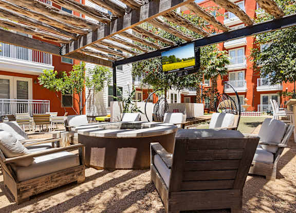 A patio with wooden furniture and a table under a wooden pergola.
