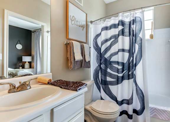 A bathroom with a white sink and a shower curtain with black lines.