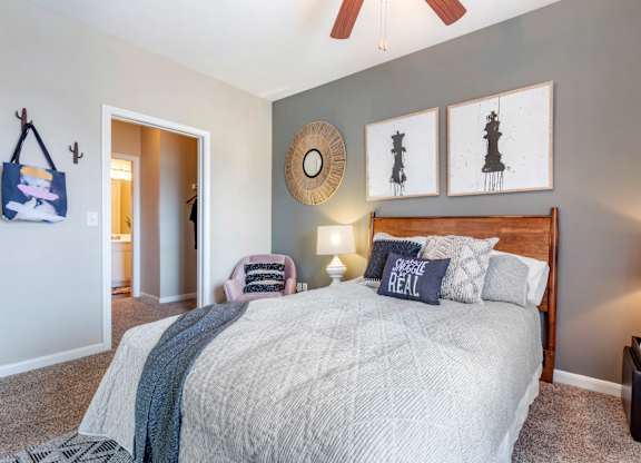 A bedroom with a bed, a ceiling fan, and a wall hanging.
