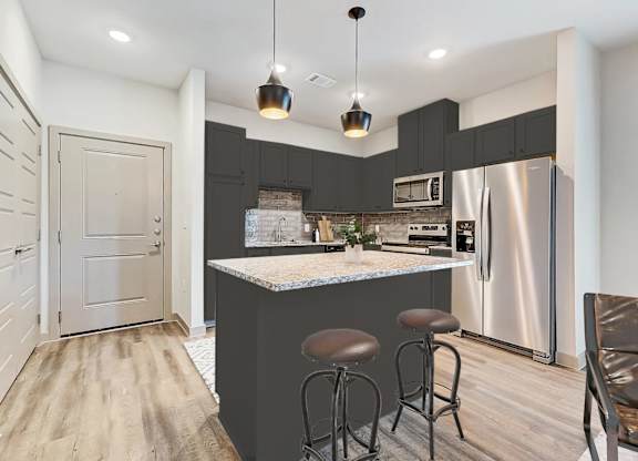 a kitchen with a bar and a stainless steel refrigerator