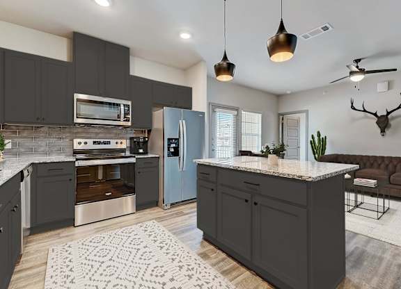 a kitchen with gray cabinets and stainless steel appliances
