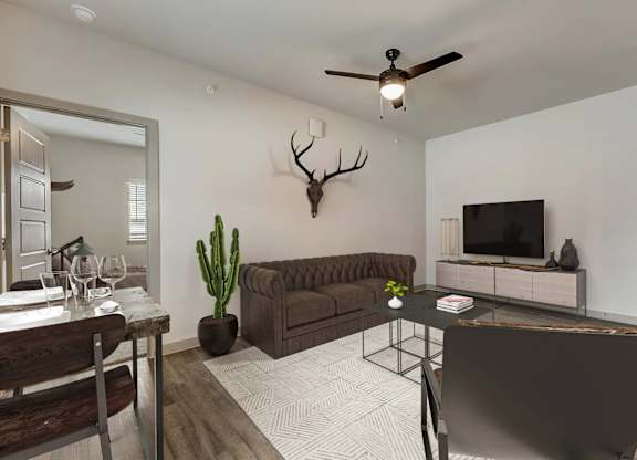 A living room with a brown couch, a black chair, a wooden dining table, and a deer head mounted on the wall.