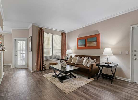 A living room with a brown couch and a painting on the wall.