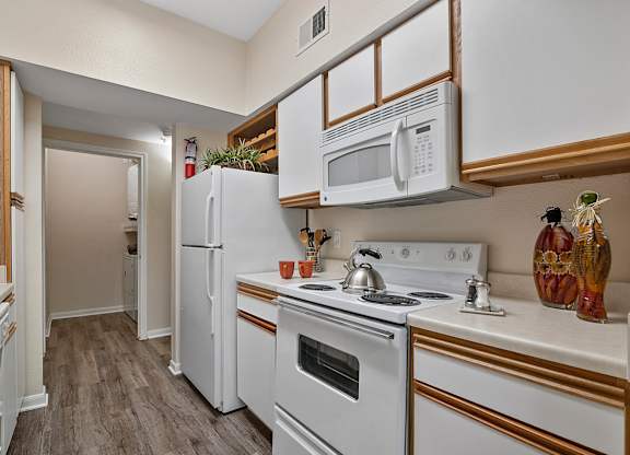 A kitchen with a white refrigerator, white oven, and white microwave.