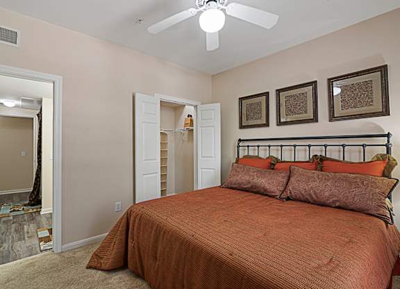 A bedroom with a bed, pillows, and pictures on the wall.