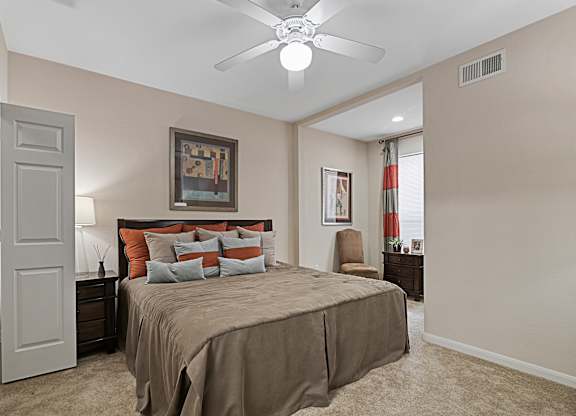 A bedroom with a bed, nightstand, and a ceiling fan.