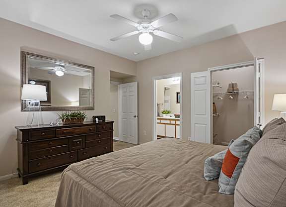 A bedroom with a large bed and a dresser with a mirror above it.