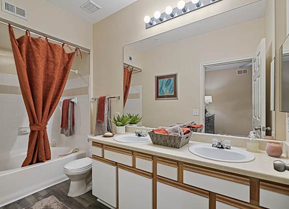 A bathroom with a white toilet, a white sink, and a brown shower curtain.