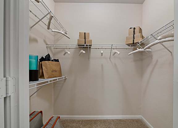A white closet with a shelf and clothes hanging on it.